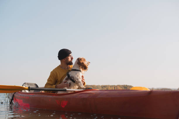 istock Kayaking with dogs: man sits in a row boat on the lake next to his spaniel. 1283546626