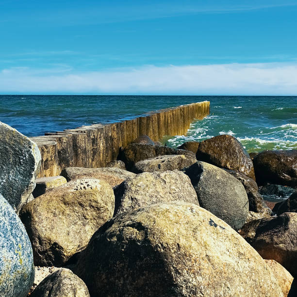Large stones lie on the beach in front of the waves