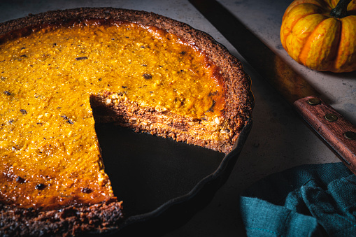 Autumn pumpkin tart cake, cheesecake with ricotta and chocolate homemade rustic in moody light