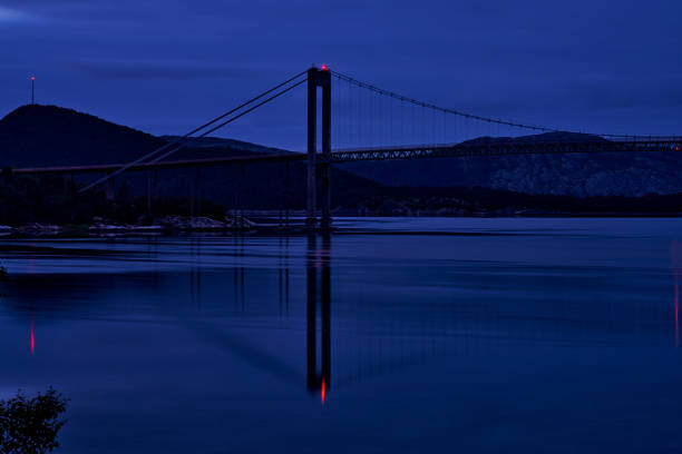 larga exposición de una flecha de puente colgante en la hora azul con reflejo en la superficie del agua - photography suspension bridge water night fotografías e imágenes de stock