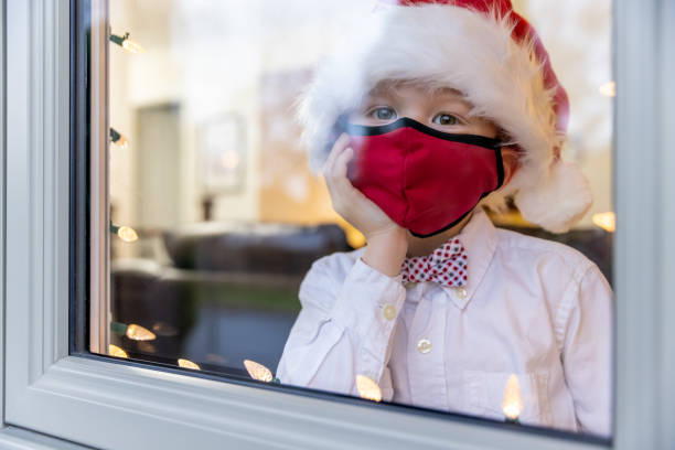 istock Young Boy Looking Through home window during the Covid-19 Pandemic 1283551393