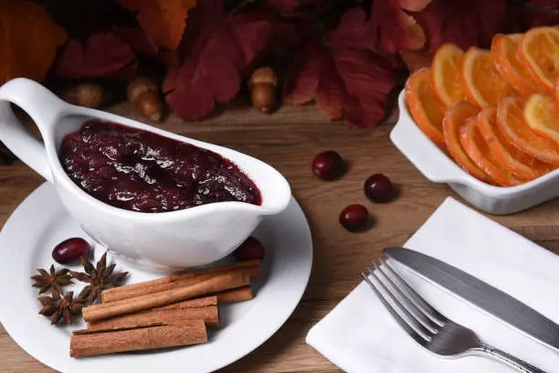 Closeup of a gravy boat with fresh homemade cranberry sauce on a Thanksgiving table.