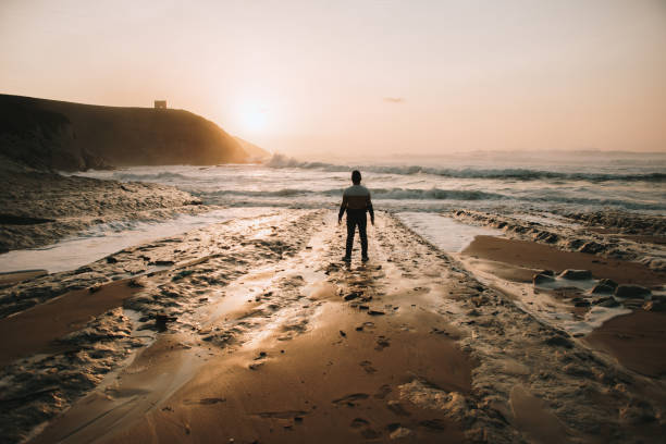 Silhouette of a man standing on a beach at sunset