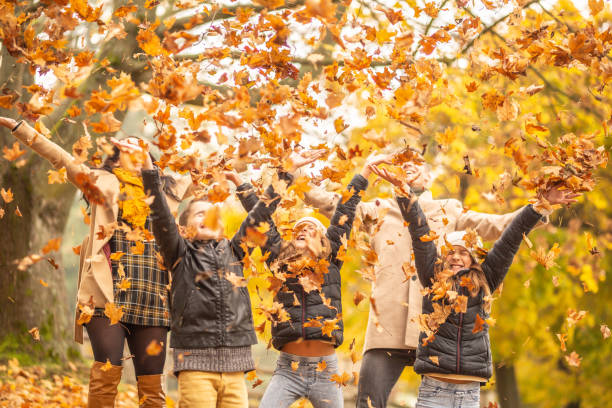 diversión familiar al aire libre en el otoño lanzando hojas caídas en el aire. - otoño fotografías e imágenes de stock