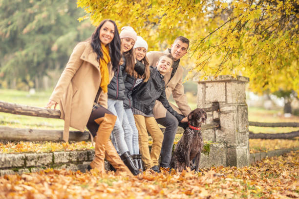 istock Young boy points in a direction where parents and his sisters look during an autumn walk in the nature with a dog. 1283554127