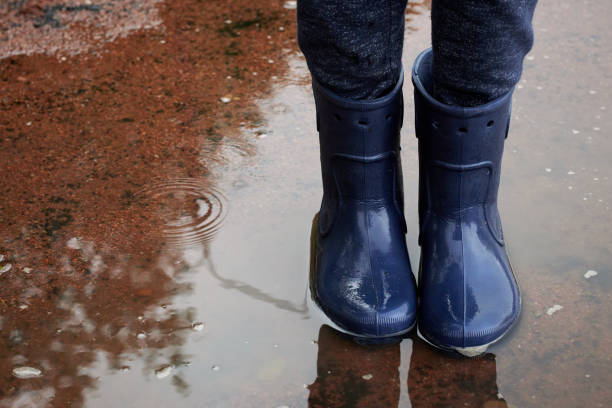 istock Childs legs in boots stand in puddle after rain. 1283555616