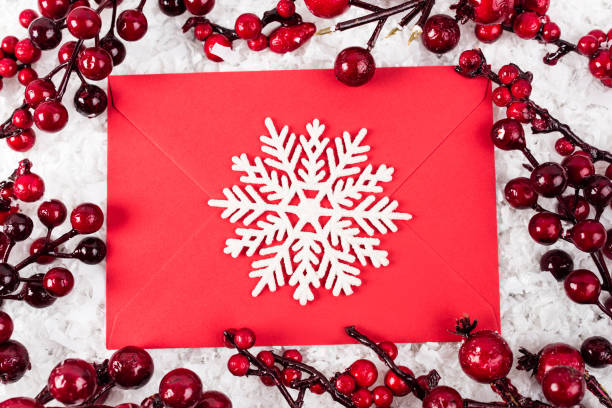 istock Top view of decorative snowflake on red envelope near branches with artificial berries on white textured background, new year concept 1283556971