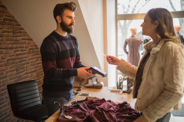 istock Employee in the store holding credit card reader and charging customer 1283557114