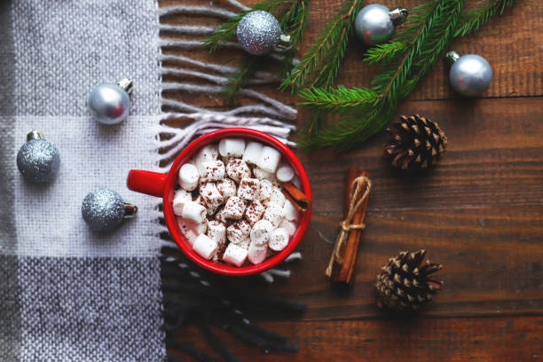 heißer kakao in einem roten becher mit marshmallows und zimt auf holzhintergrund mit karierten, weihnachtskugeln, tannenzapfen und tannenzweigen. gemütliches winterkonzept. nahaufnahme, selektiver fokus, flach liegend, ansicht von oben - comfort food high angle view directly above close up stock-fotos und bilder