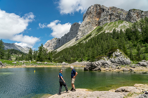 Mature couple standing on the rock and enjoying the panoramic view at the Black Lake in Triglav National Park