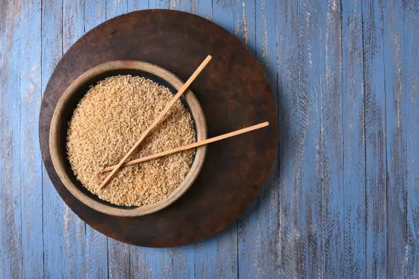 Brown Rice and Chop Sticks on a rustic blue wood table. Top view with copy space.