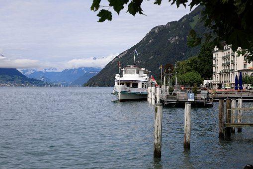 Brunnen, Switzerland - August 31, 2020: The motor ship Titlis stopped at the quay on Lake Lucerne. It is the landscape of a tourist town situated by the water. This is one of the countless wonderful places in Switzerland, which is a tourist attraction often visited by many tourists from all over the world.