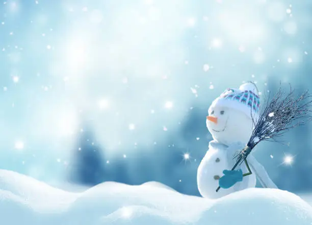 Merry Christmas and happy New Year greeting card with copy-space. Happy snowman with a broom in hand, standing in Christmas landscape. Snow background. Winter fairytale.