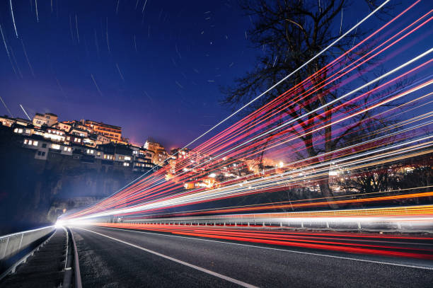 Long exposure image of a city during the rush hour in the dark. Car light trails, and street lamps.