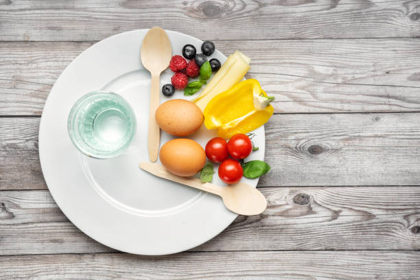 Interval fasting diet concept represented with a plate and products Interval fasting diet. Intermittent fasting concept represented with a plate and products on gray background. Healthy lifestyle. Fat loss concept. Top view fast water stock pictures, royalty-free photos & images