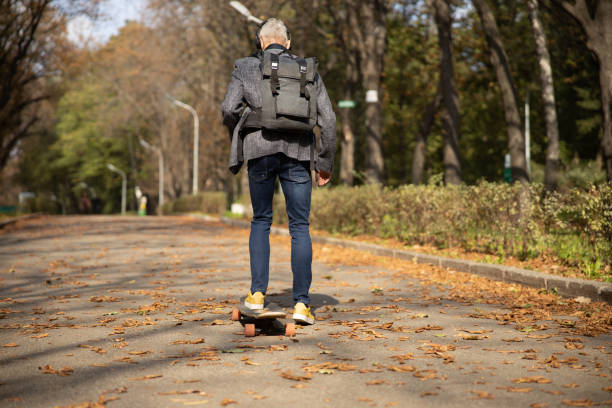 istock Stylish man going skateboarding in sunny park 1283563896