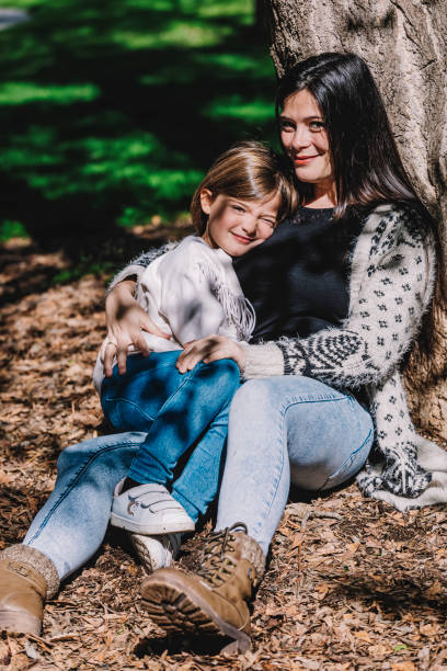 istock Mom and daughter are sitting near a tree 1283564228