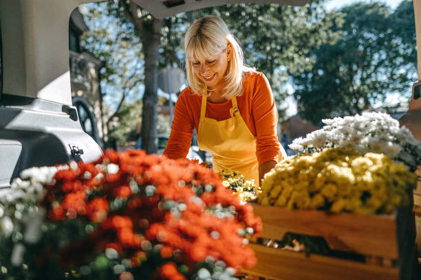 istock Woman unloading crates of fresh flowers from car trunk 1283567145