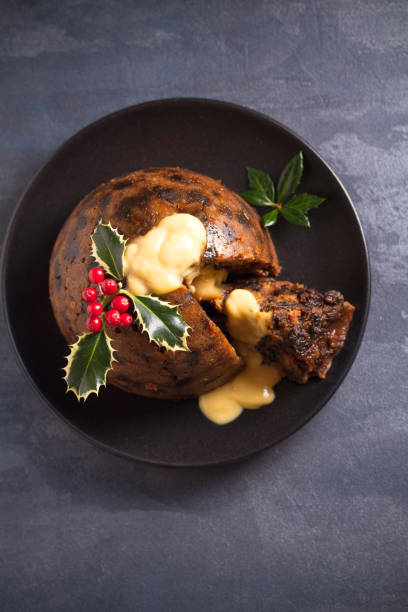 Richly spiced Christmas pudding cake with custard and Christmas decorations