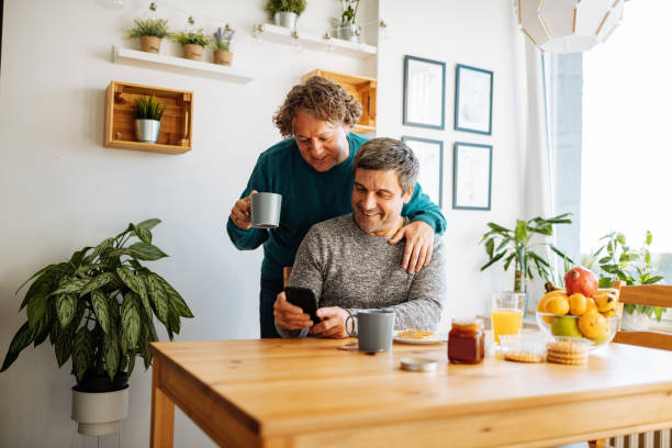 Mature gay couple eating breakfast Mature gay couple working from home during quarantine gay dinner table stock pictures, royalty-free photos & images