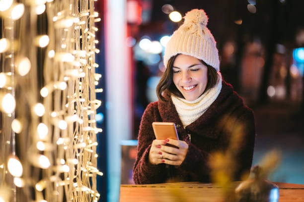istock Woman checking social media on phone among Christmas string lights 1283571419