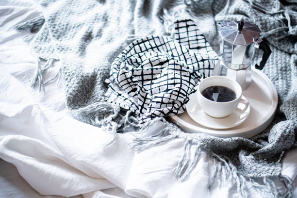 istock Cup of coffee on tray in cozy winter bad with wool blanket 1283572942