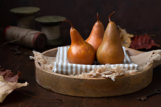 istock Close-up of Three Pears on a Wooden Tray in a Rustic Setting 1283577859