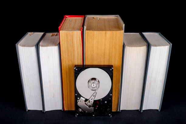 istock Old paper books and computer disk. Paper and digital data carrier. Dark background. 1283583173