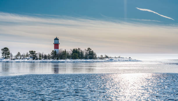 vista molto ravvicinata del faro bianco rosso nel mezzo di un'isola ghiacciata e innevata nel freddo mar baltico, in parte acqua aperta, ghiaccio sottile che riflette la luce del giorno. cielo blu, brezza leggera. svezia settentrionale, umea - partly foto e immagini stock