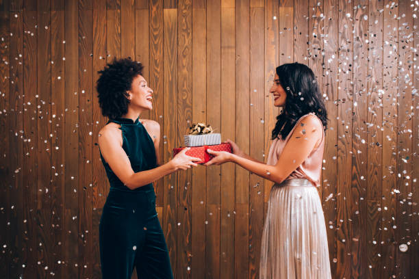 istock Merry Christmas: Two Smiling Young Women Exchanging Christmas Presents at a Party 1283586083