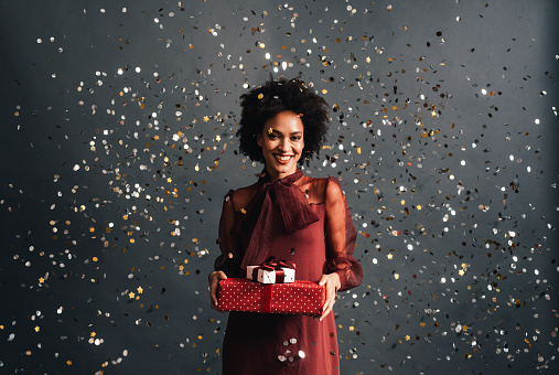 Beautiful smiling woman holding Christmas presents, a studio shot (looking at camera).