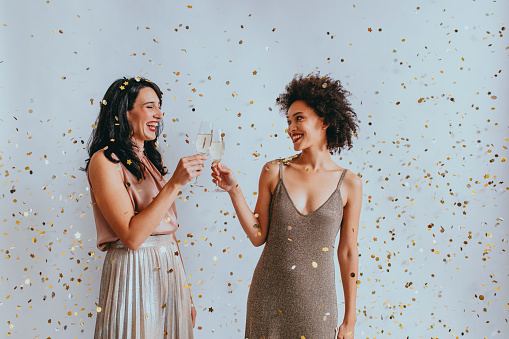 Party time: two elegant young women drinking champagne to celebrate together.