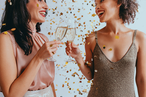 Party time: two elegant young women drinking champagne to celebrate together.