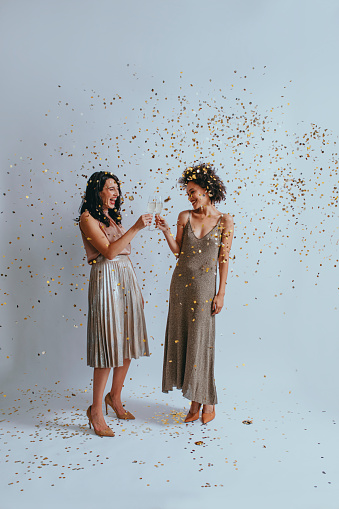 Party time: two elegant young women drinking champagne to celebrate together.