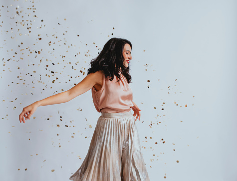 Confetti party: a happy woman feeling festive and dancing (white background, copy space).