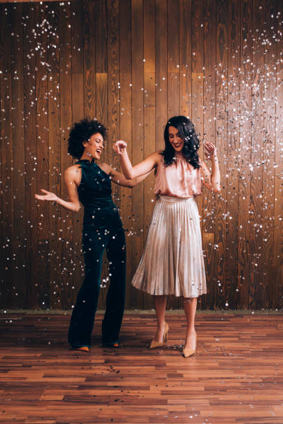 istock Party Time: Two Beautiful Women Dancing in Confetti Rain, Feeling Festive Concept 1283586131