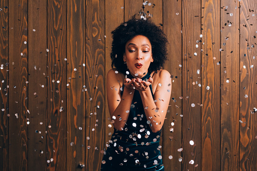 Beautiful woman blowing confetti at a party, celebration concept (copy space).