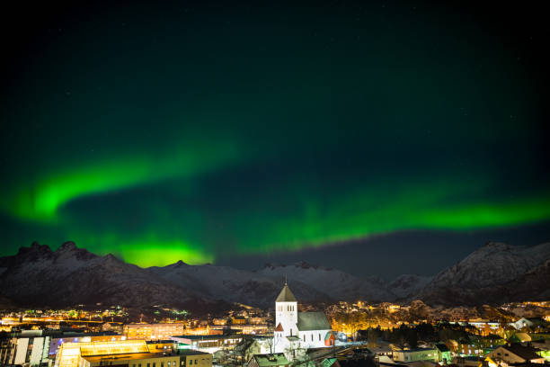 Dancing green polar lights over the town Svolvaer on the Lofoten islands in Norway at night in winter with snow Dancing green polar lights over the town Svolvaer on the Lofoten islands in Norway at night in winter with snow harbor of svolvaer in winter lofoten islands norway stock pictures, royalty-free photos & images