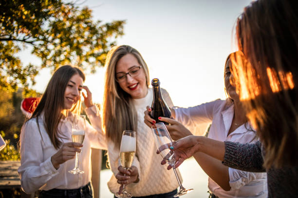 大晦日を祝う若い女性 - シャンパンで新年のお祝い - 若い女性、学生は、シャンパンを飲むことによって美しい自然の中で湖で新年を祝う - new years day new years eve new year ethnic ストックフォトと画像