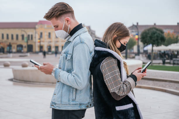 istock Couple wearing face masks and using their smartphones 1283589765