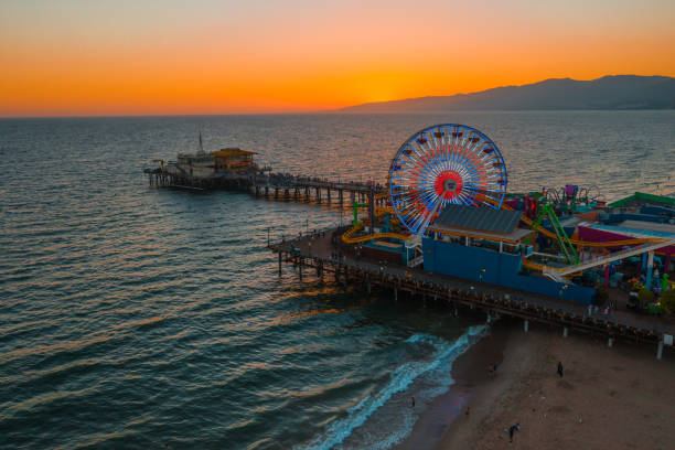 santa monica pier at sundown with lights reflected in the pacific ocean - santa monica pier santa monica beach night amusement park imagens e fotografias de stock