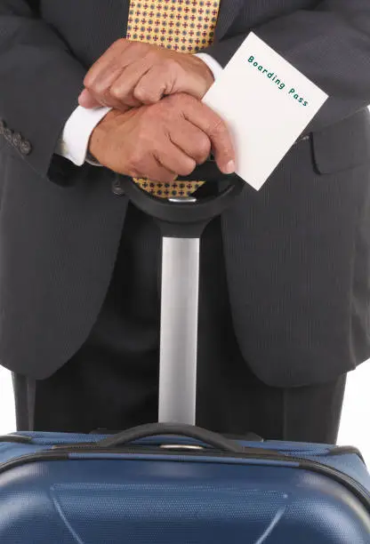 Business Traveler holding luggage handle and boarding pass in vertical format. Close up of luggage hands and white card with easily altered type for you to add your own message