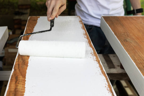 istock Man Painting Wood Boards with Paint Roller and White Paint 1283595969