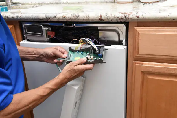 Closeup of a appliance repairman unplugging the control panel to a broken dishwasher.