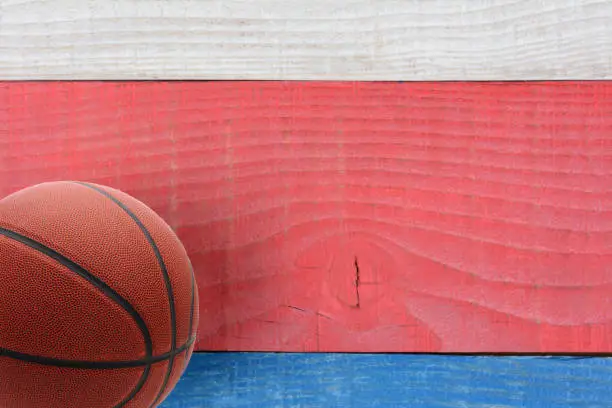 High angle shot of a basketball on a red, white and blue picnic table. Horizontal format with copy space. Suitable for American Holidays: 4th of July and Memorial Day,
