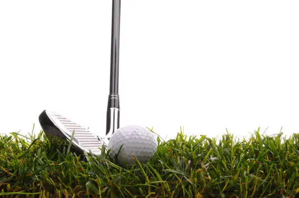 Closeup of a Golf Ball and Iron in tall grass with a white background.