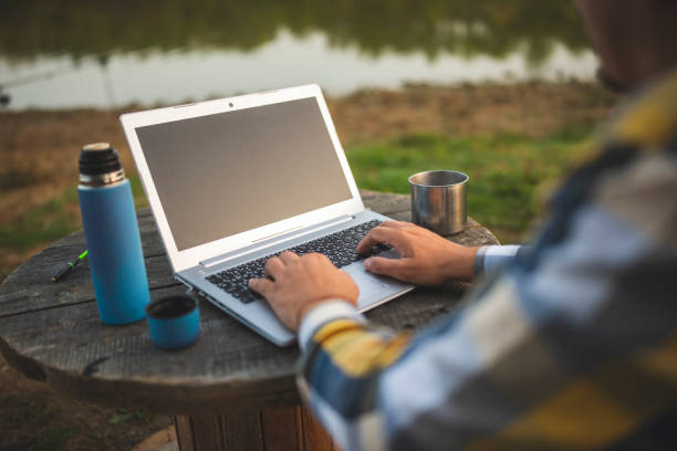 istock Unrecognizable man with laptop working outdoors in the nature 1283599965