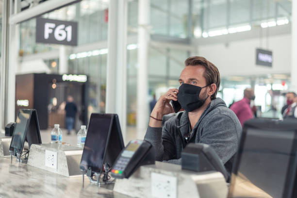 istock Man in protective face mask talking on mobile phone at airport boarding gate 1283600062