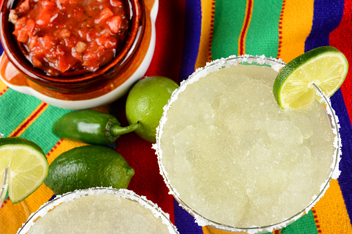 Cinco de Mayo Concept: Margaritas and Salsa on a colorful  table cloth, with limes, and peppers.