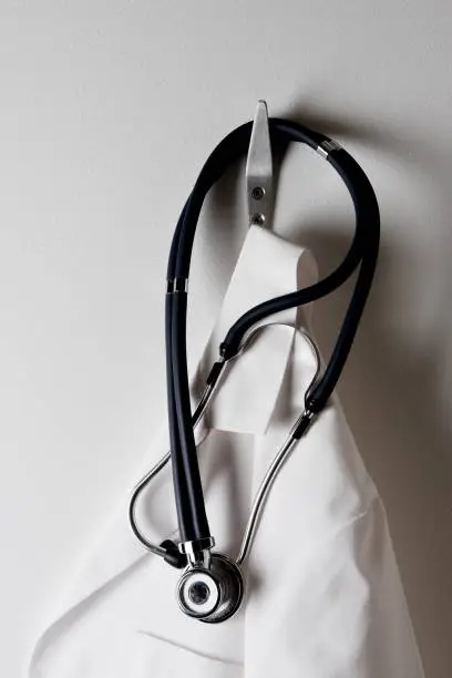 Closeup of a Doctors White Lab Coat Hanging on a Hook with Stethoscope.